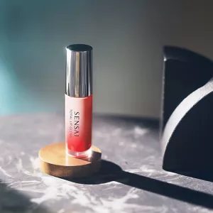 Total Lip Gloss esposto su una base rotonda in legno appoggiata su un piano in marmo
